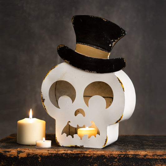 Skull-shaped candle holder with a top hat and candles on a dark background